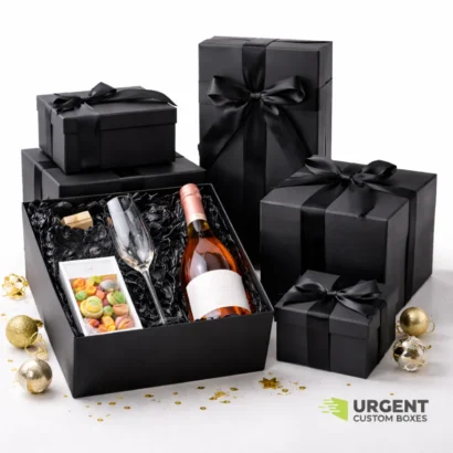 Matte black gift boxes with ribbon, featuring a wine bottle, glass, and treats, on a clean white background