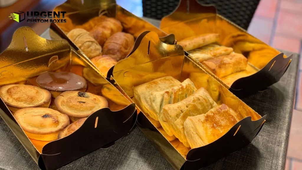 Assorted croissants and pastries in gold foil lined bakery packaging