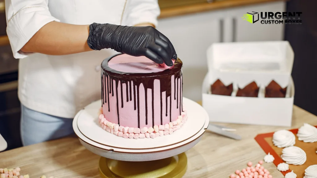 Baker decorating custom drip cake next to white bakery boxes