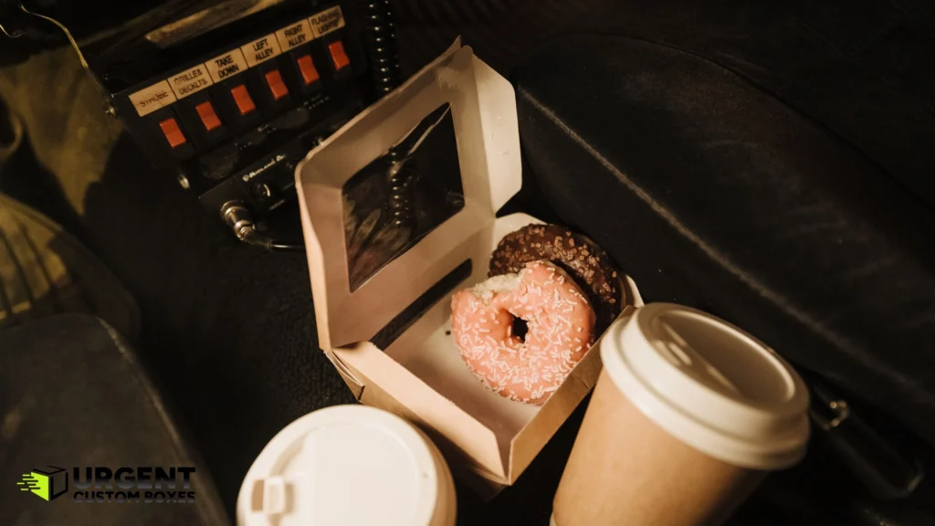 Frosted donuts inside a small window pastry box on a car seat
