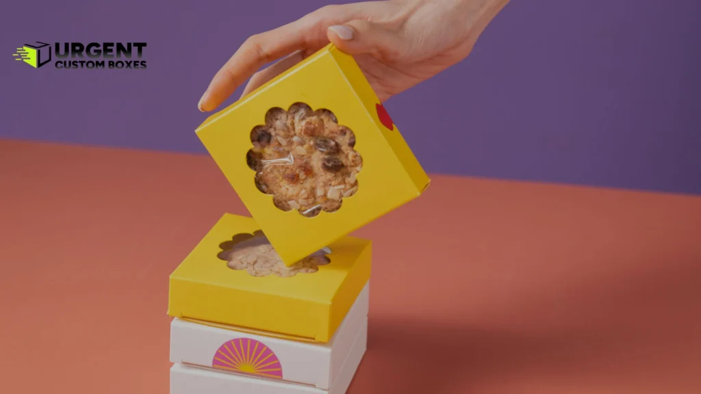 Hand stacking small yellow custom cookie boxes with die-cut windows