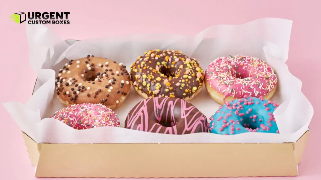 Six colorful frosted donuts inside a kraft paperboard bakery box