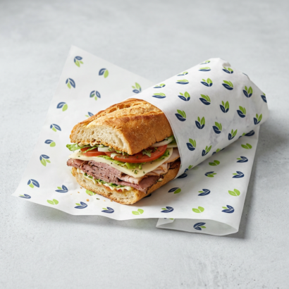 Sub sandwich wrapped in white custom printed dry wax paper with a repeating logo pattern
